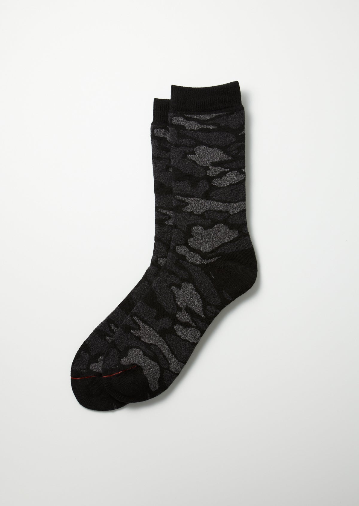 Black and grey pile camo crew socks with a textured knit camouflage pattern, dark cuffs, and a subtle red toe stitch, laid flat.