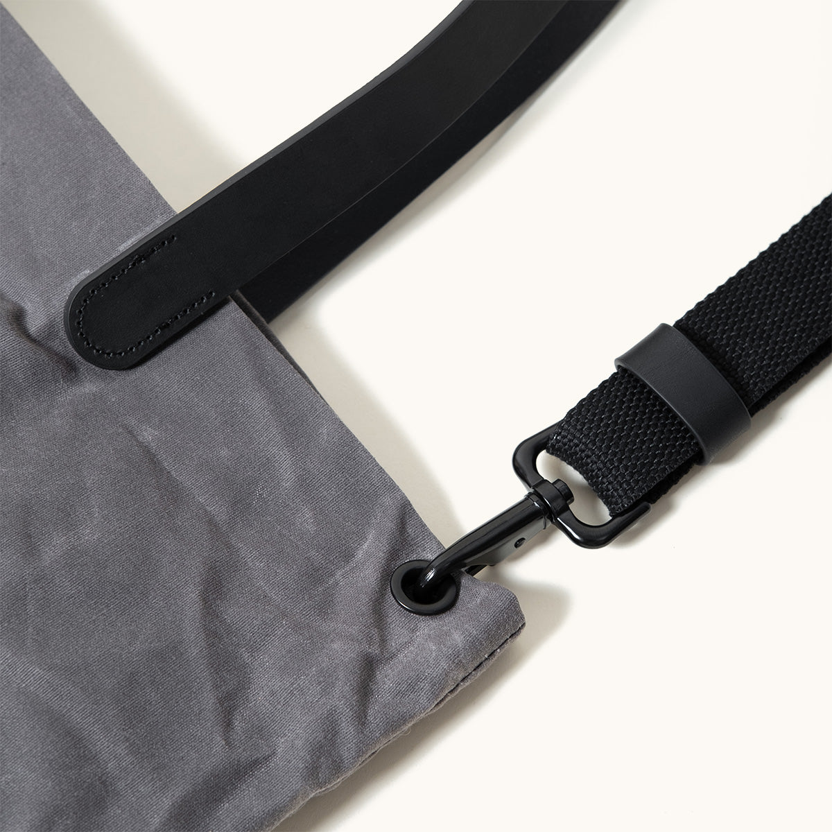 Slate grey waxed canvas tote bag with black strap, black metal clasp, and black grommet.