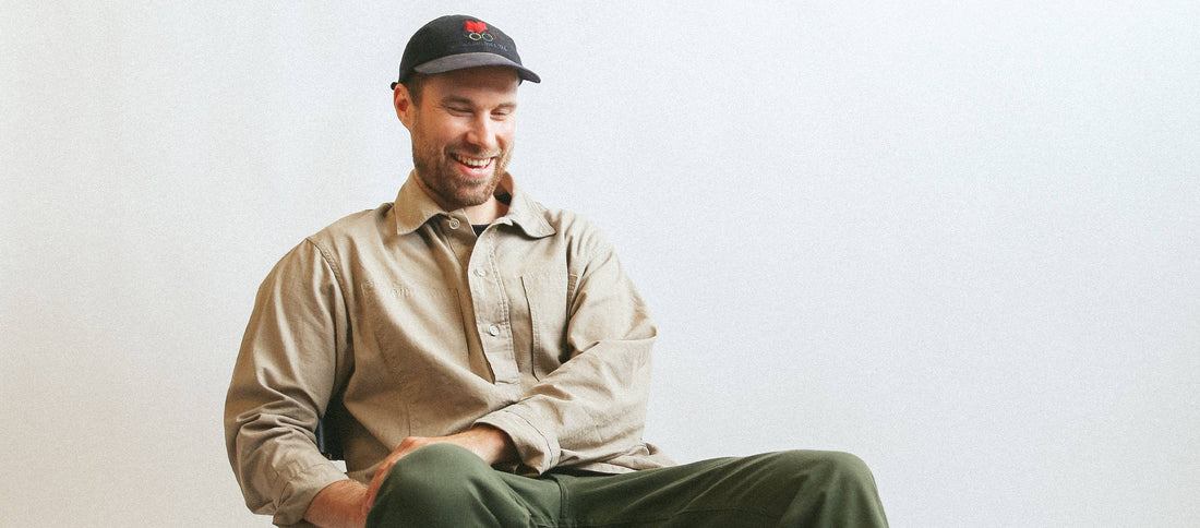 Jukka Lehtinen, Tarvas Footwear founder, smiles warmly while seated casually in a beige shirt and black cap.