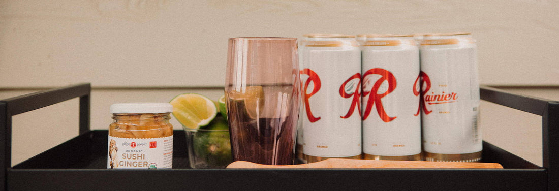 Tray with Rainier beer cans, sushi ginger jar, lime wedges, and a glass—ready for a refreshing Ginger Shandy.