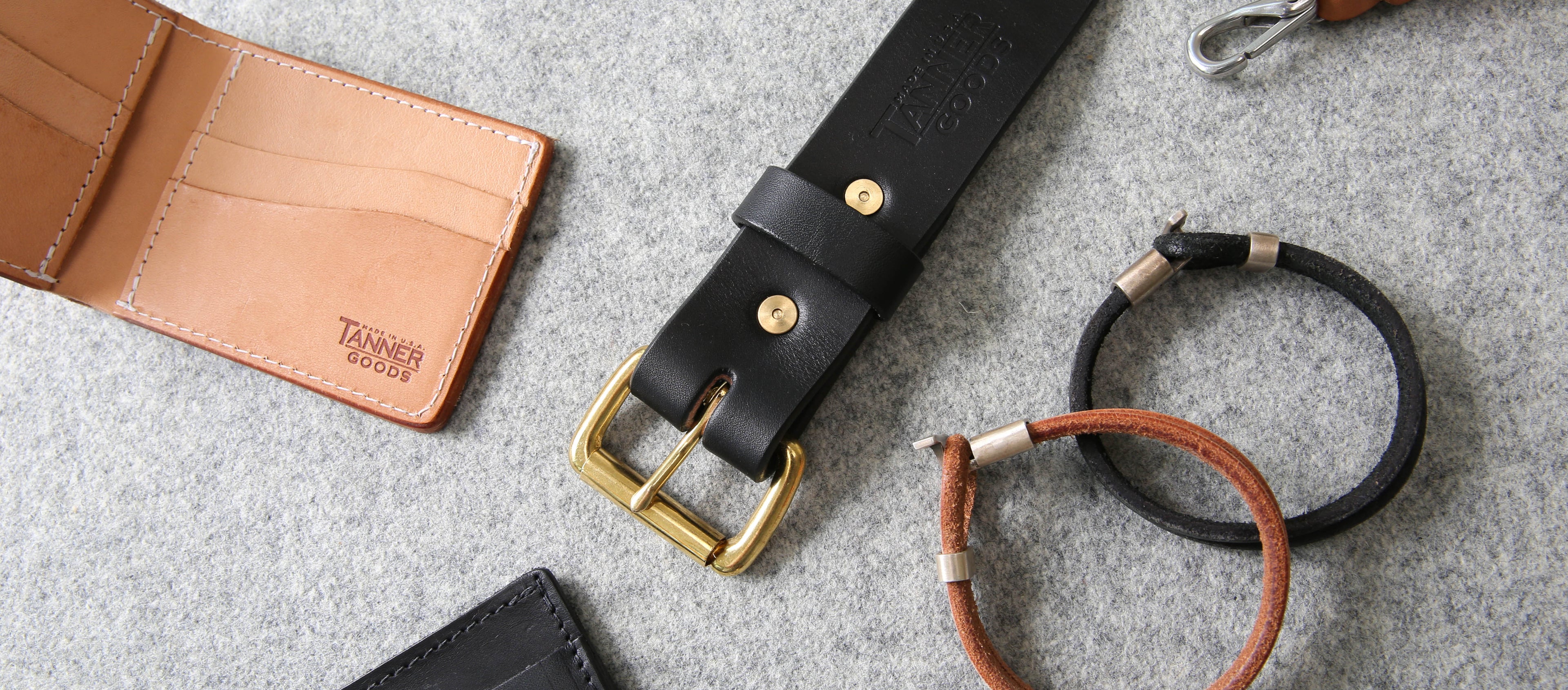Rich leather wallet, belt, and key rings in tan and black with gold hardware, showcasing timeless craftsmanship.