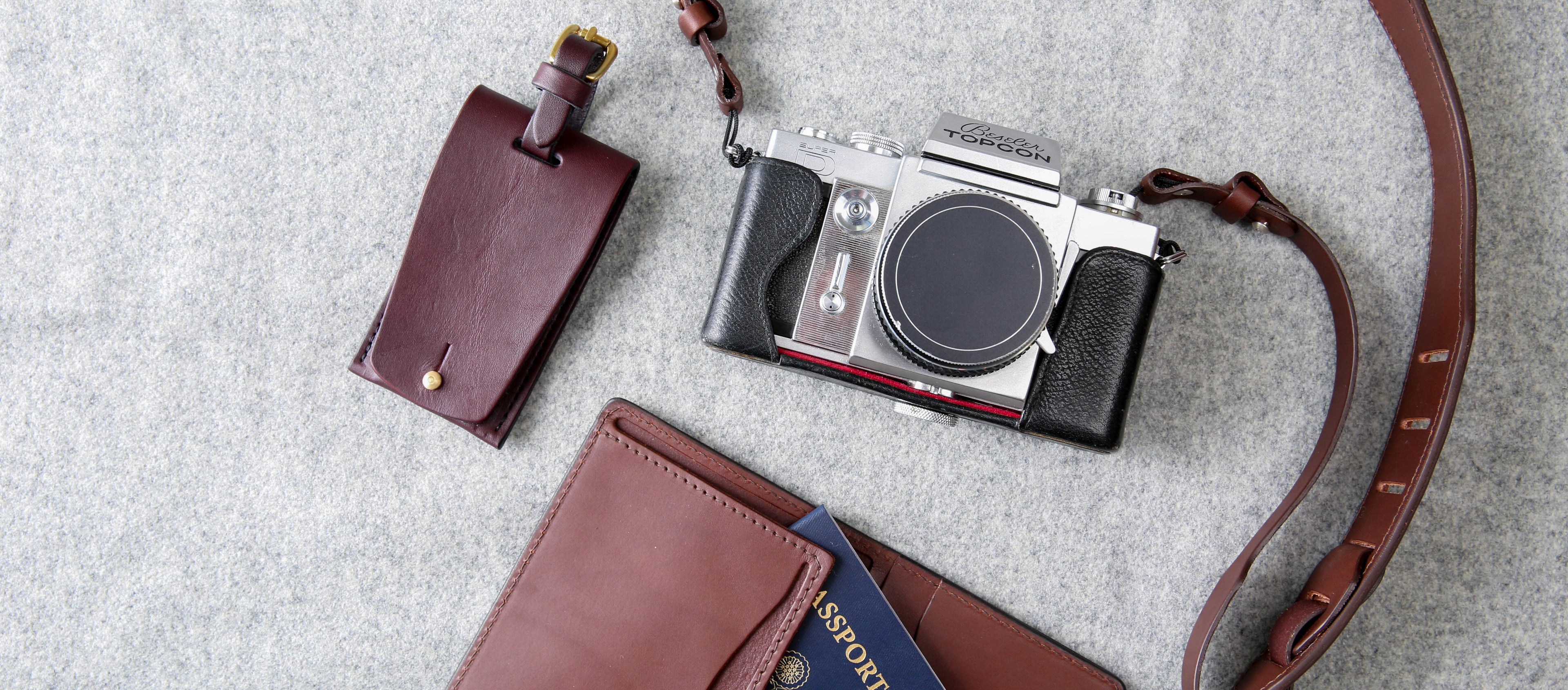 Rich brown leather travel essentials with vintage camera, passport holder, and luggage tag for the modern adventurer.