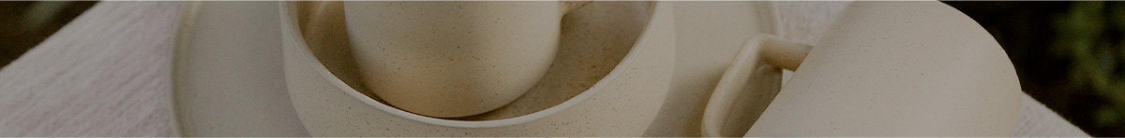 Earthy speckled ceramic mugs and bowls in warm neutrals, handcrafted for cozy, minimalist tableware.