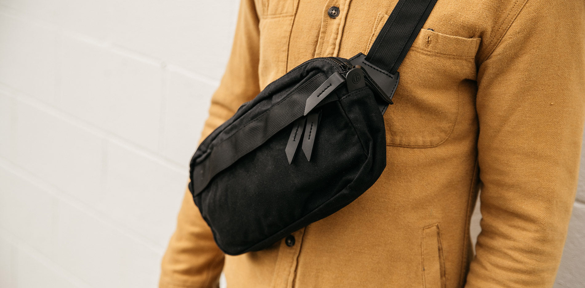 Minimal black crossbody bag on tan shirt, urban essentials for daily adventures.