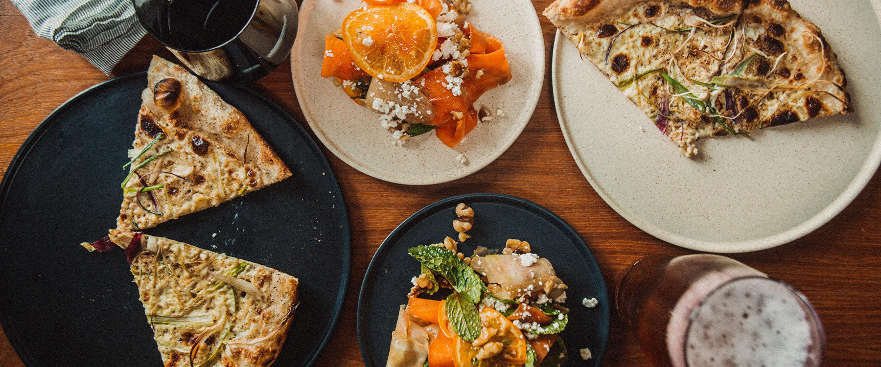 Earthy ceramic plates in black and speckled beige serve gourmet dishes, evoking rustic elegance and modern dining.