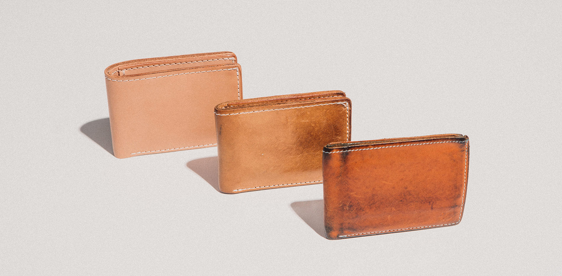 Three Utility Bifolds showing off their different aging patinas with the first showing little to no signs and the third showing marks, scuffs and a completely darker color.
