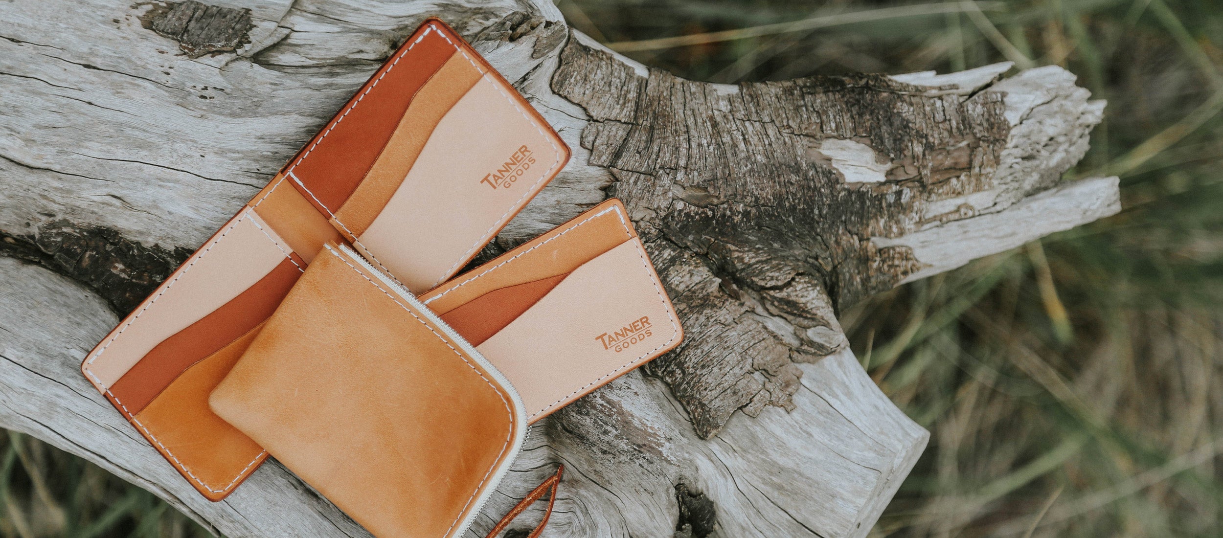 Warm-toned leather wallets in desert hues rest on weathered wood, evoking rustic adventure and timeless craftsmanship.
