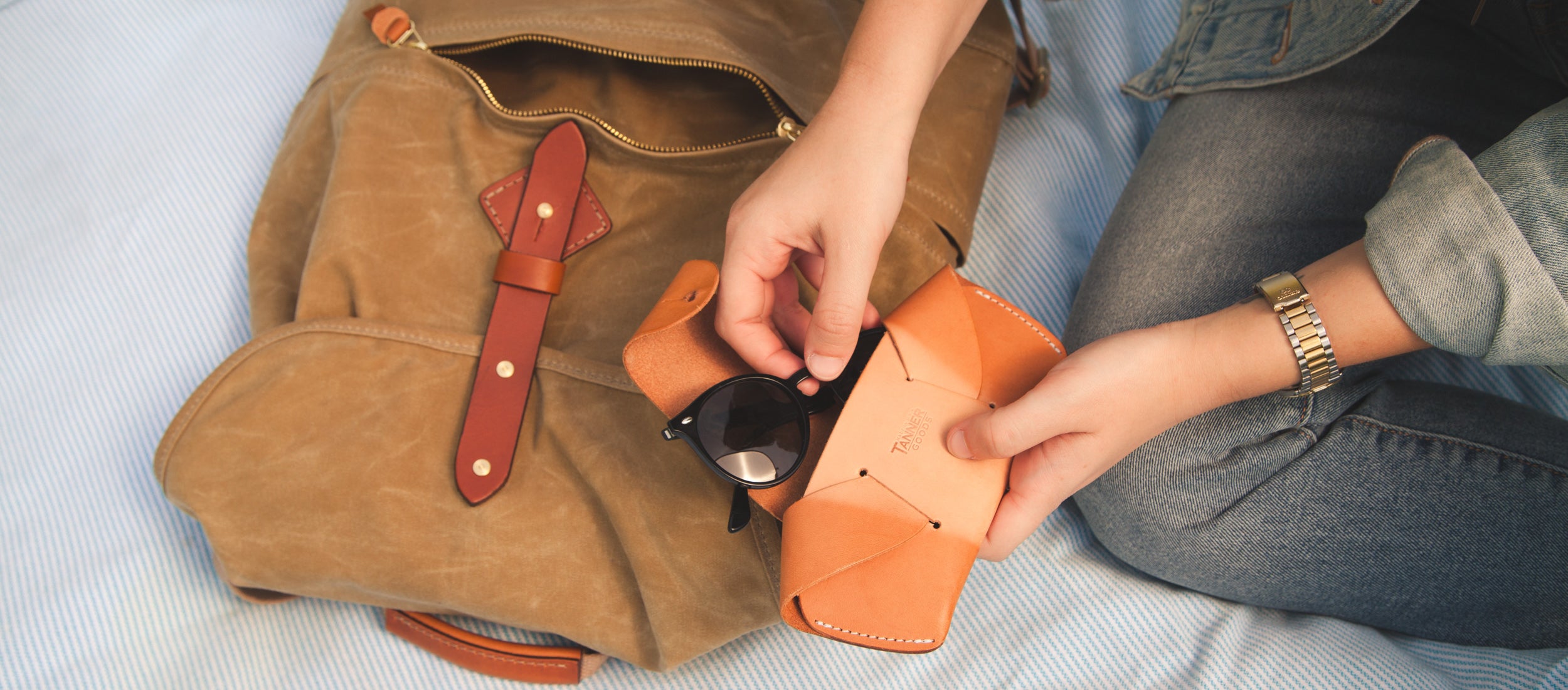 Women’s Capsule: tan leather bag, orange wallet, sunglasses, denim — minimalist, everyday essentials in warm, earthy tones.