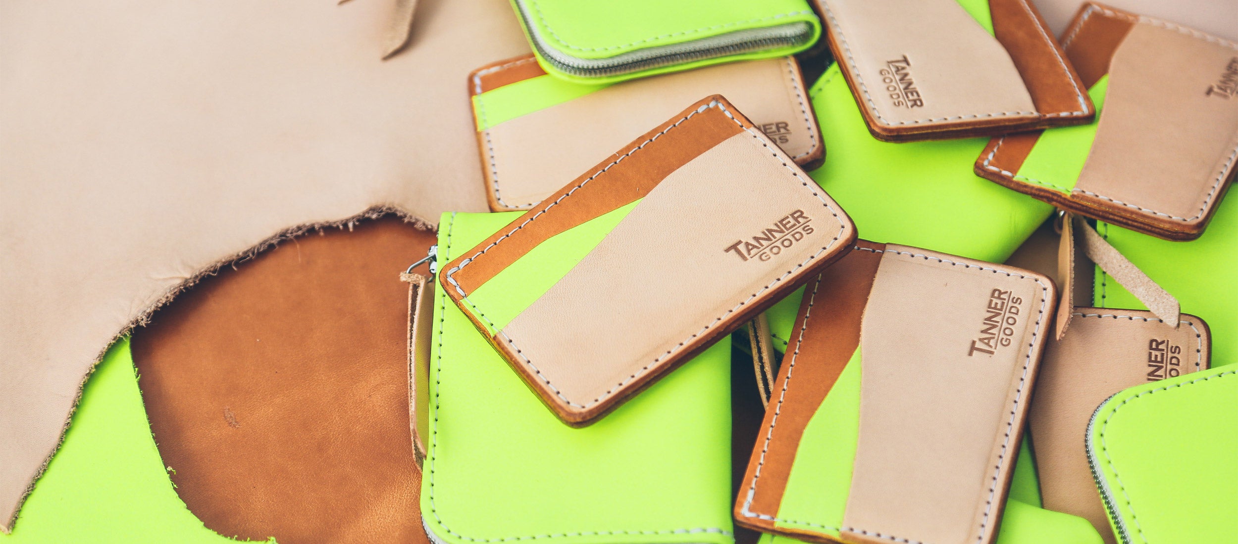 Vibrant neon green and tan leather wallets, cardholders, and coin purses in bold, modern designs.