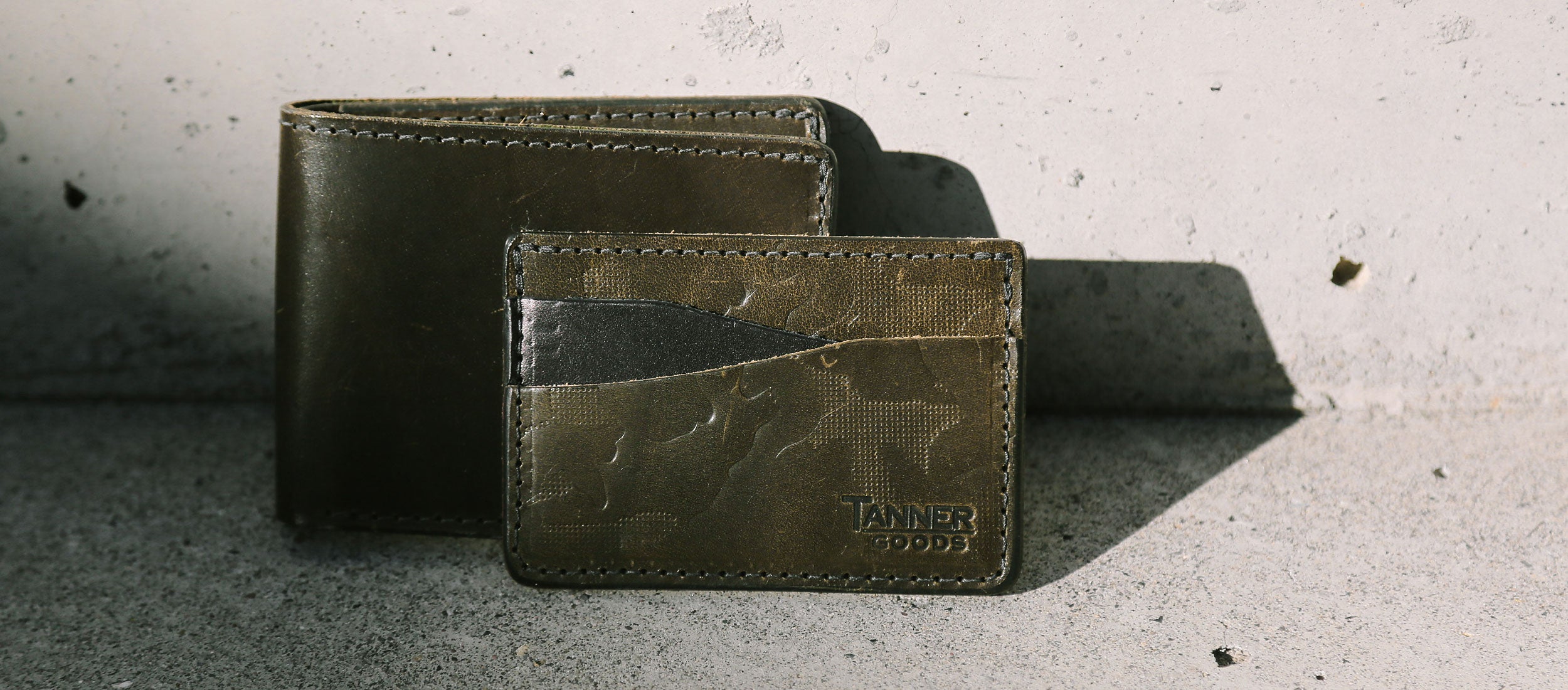 Olive green leather wallets with foliage camo texture, rugged urban style, Tanner Goods branding.