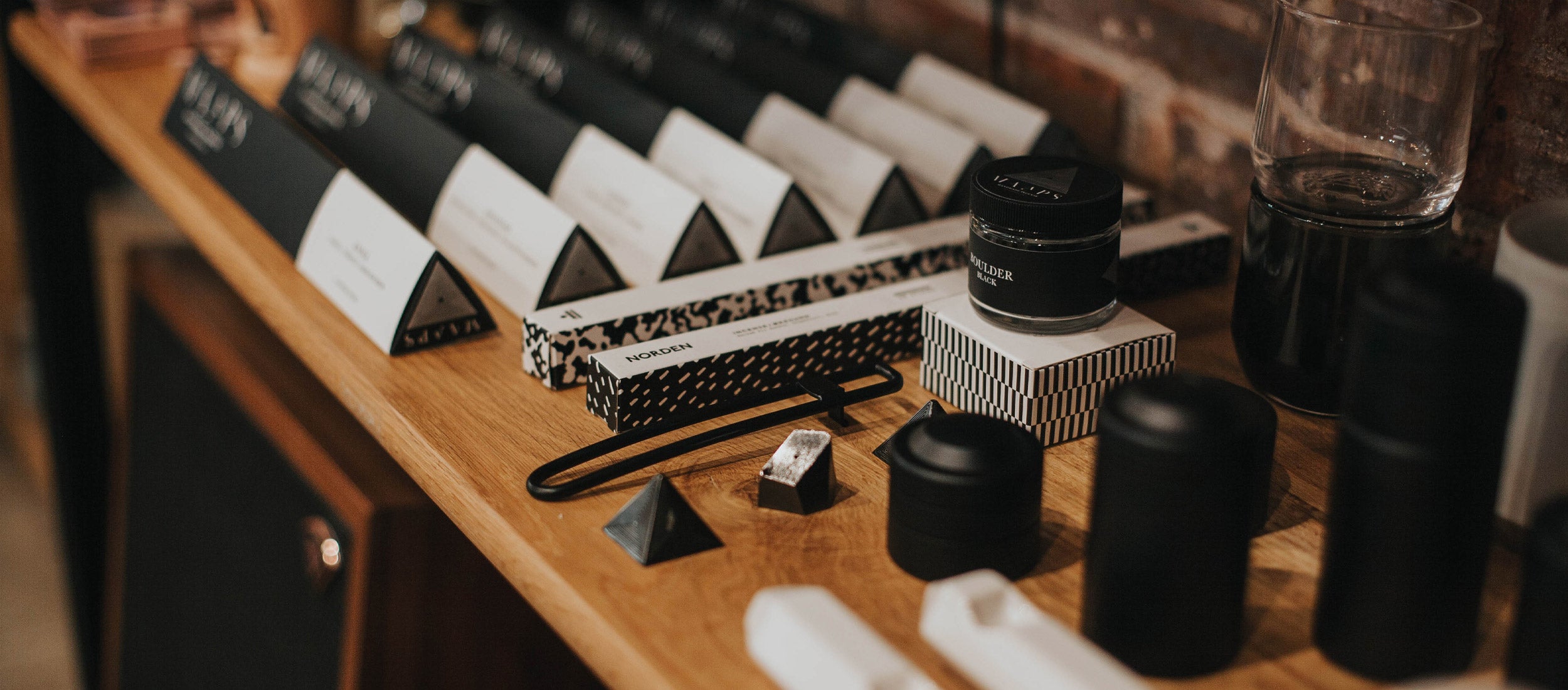 Minimalist incense collection in black and white geometric packaging, featuring sleek cones, sticks, and diffusers on warm wood.