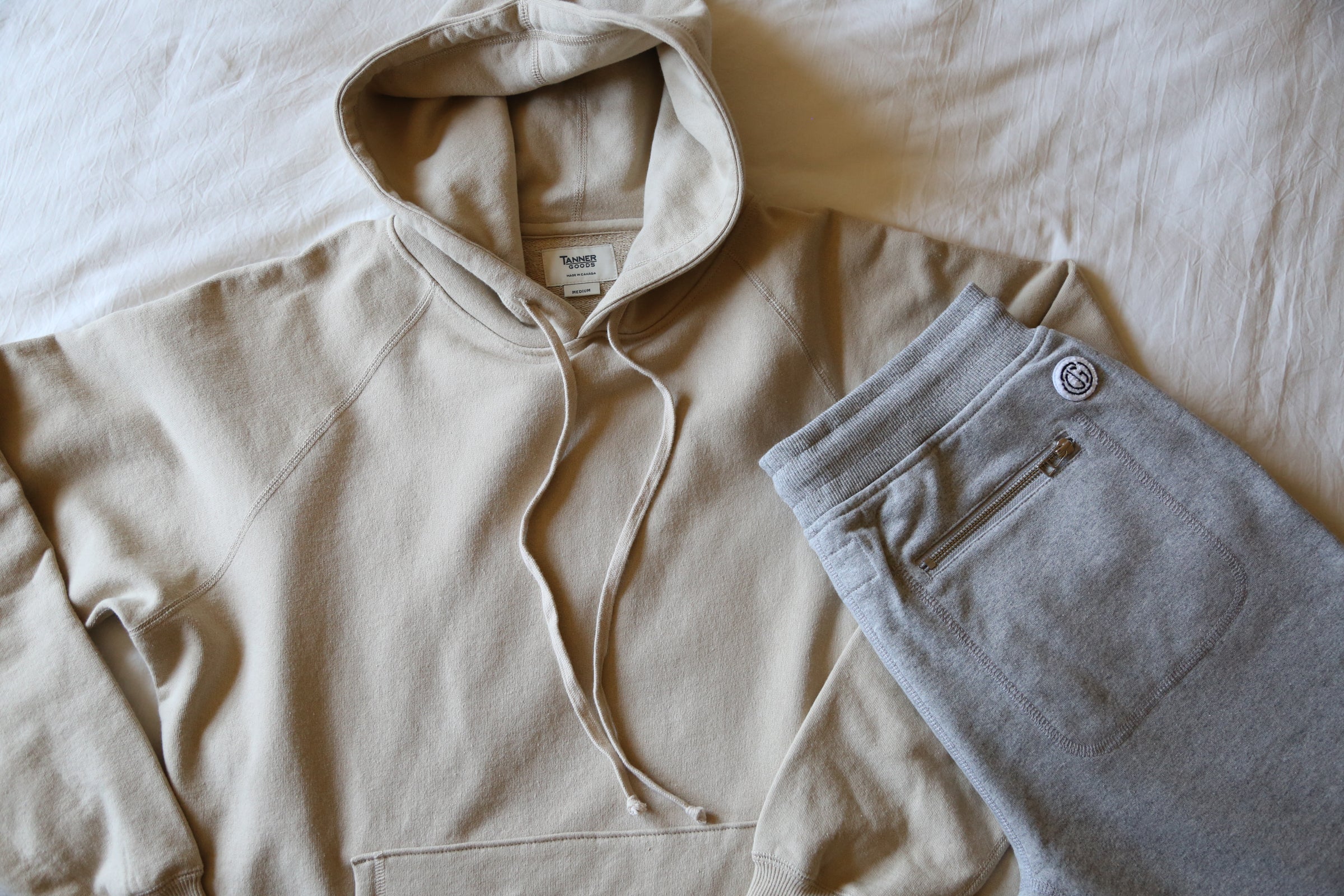 Soft beige hoodie and gray sweatpants with zipper pocket, minimalist loungewear for relaxed comfort.