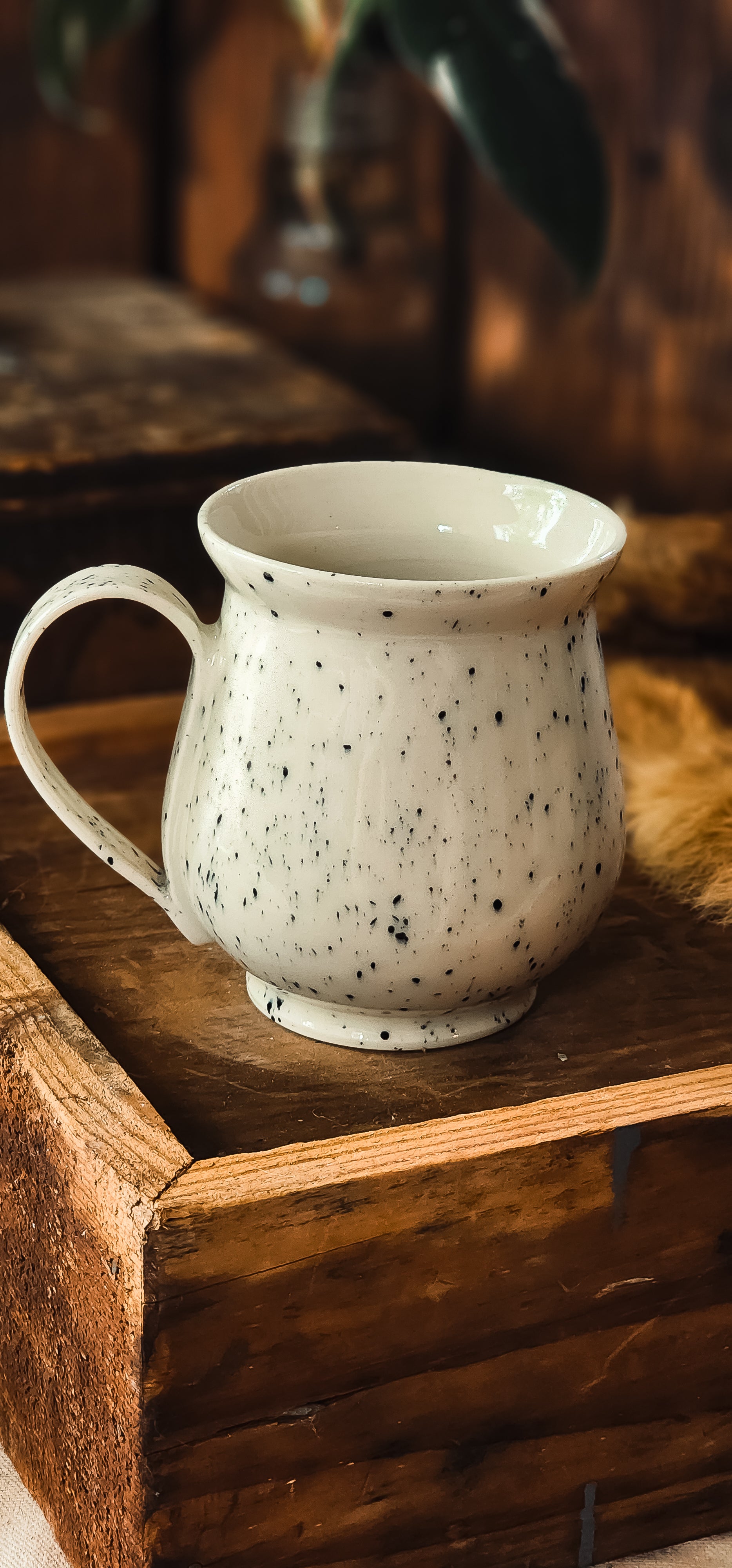 Lost lake mug, speckled white with black flecks, sitting in a rustic wooden crate.