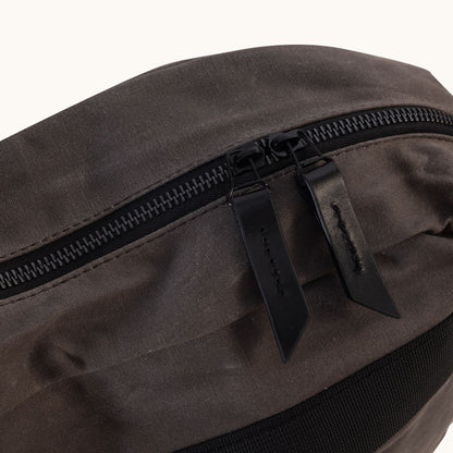 Slate Grey Waxed Canvas Crossbody bag with a black zipper and leather pull tabs, close-up.