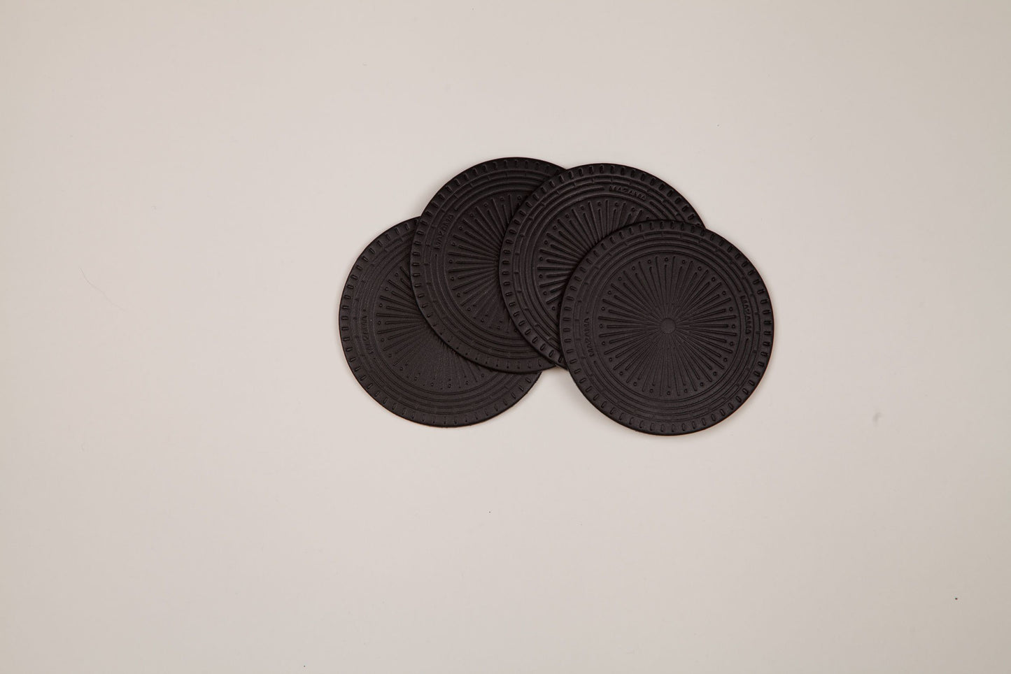Dark grey textured Coaster Set of 4 with a radial pattern and 'MAZAMA' text, partially overlapping.