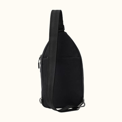 Black fabric sling bag by Hedgren, shown in a side view with a zippered pocket, adjustable strap, and metal D-rings.