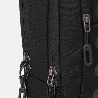 Black sling bag by Hedgren, featuring a textured fabric and multiple dark grey zippers with branded pull tabs.