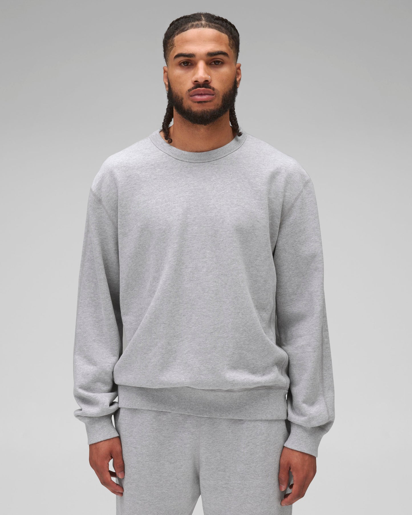 Grey midweight terry standard crewneck worn by a person with braided hair and a nose ring, paired with matching sweatpants.