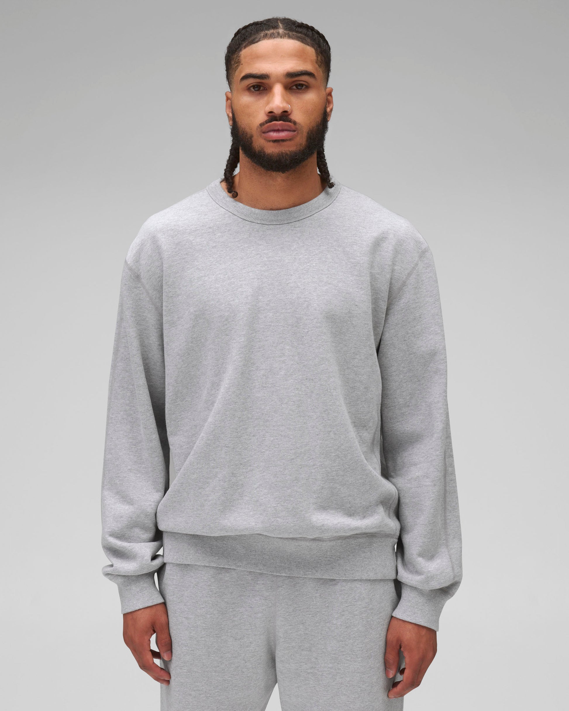 Grey midweight terry standard crewneck worn by a person with braided hair and a nose ring, paired with matching sweatpants.