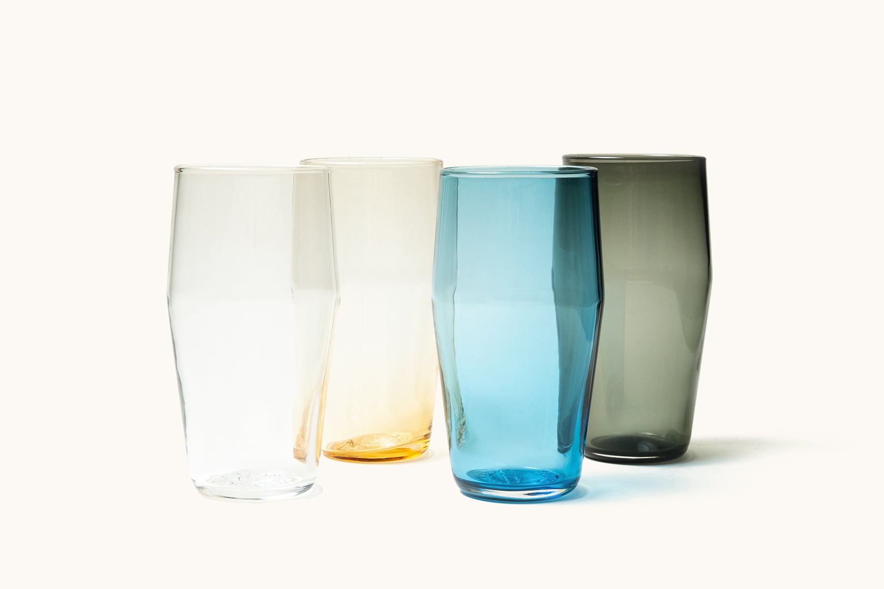 Set of four glass standard pint glasses in clear, yellow, blue, and grey.