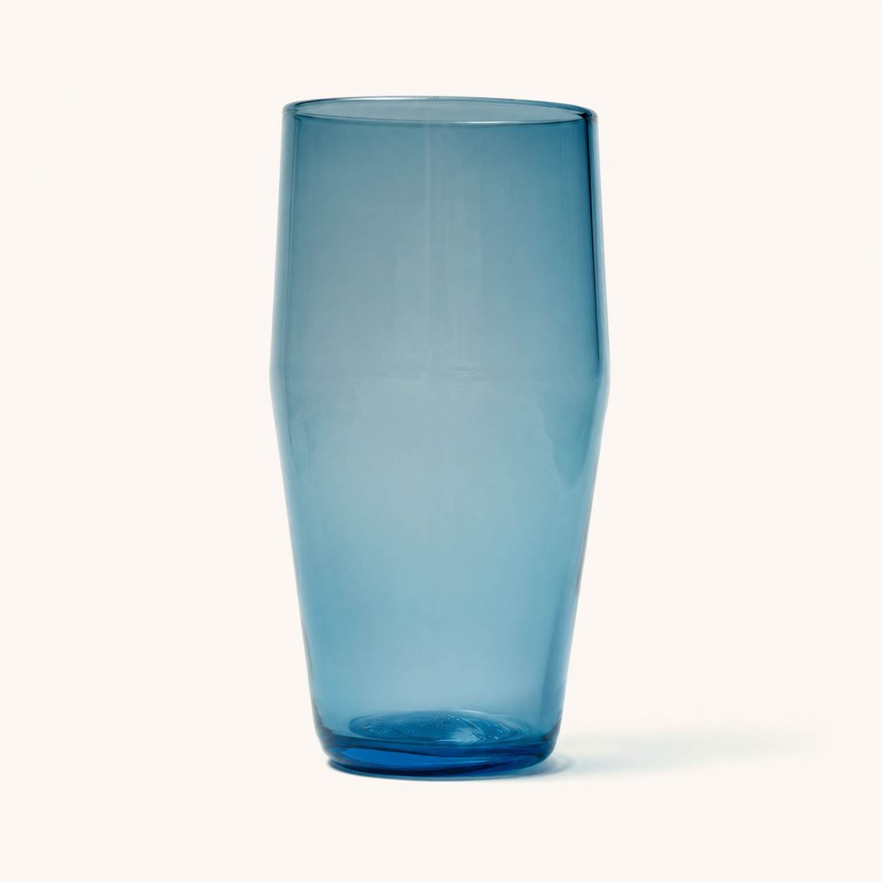 Teal tinted standard pint glass with faceted sides and thick base, front view on white background