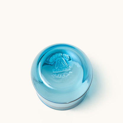 Blue cocktail glass by Mazama with an embossed logo on the bottom, angled view.