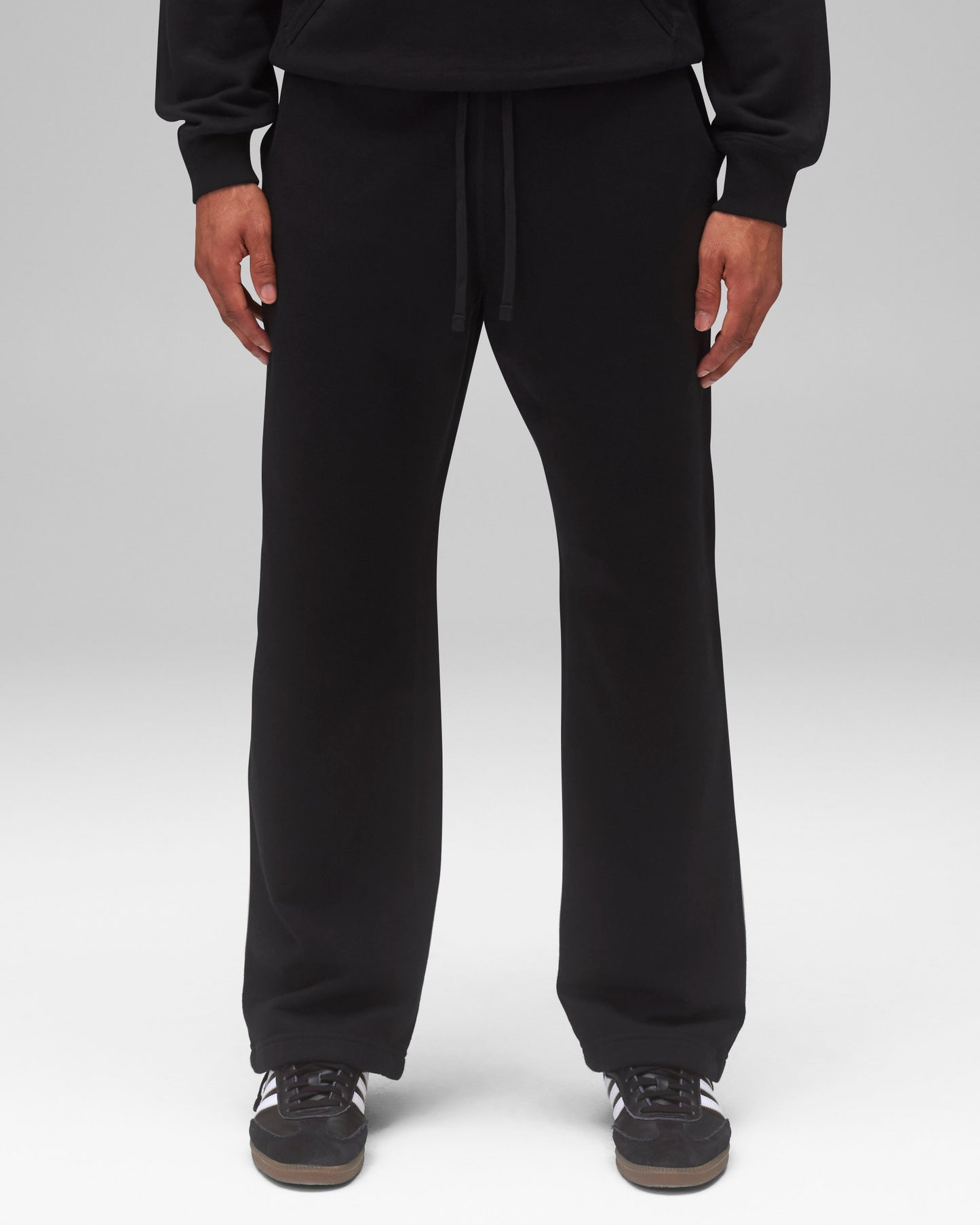 Black Midweight Terry Relaxed Sweatpants with a drawstring, worn with a black hoodie and sneakers.