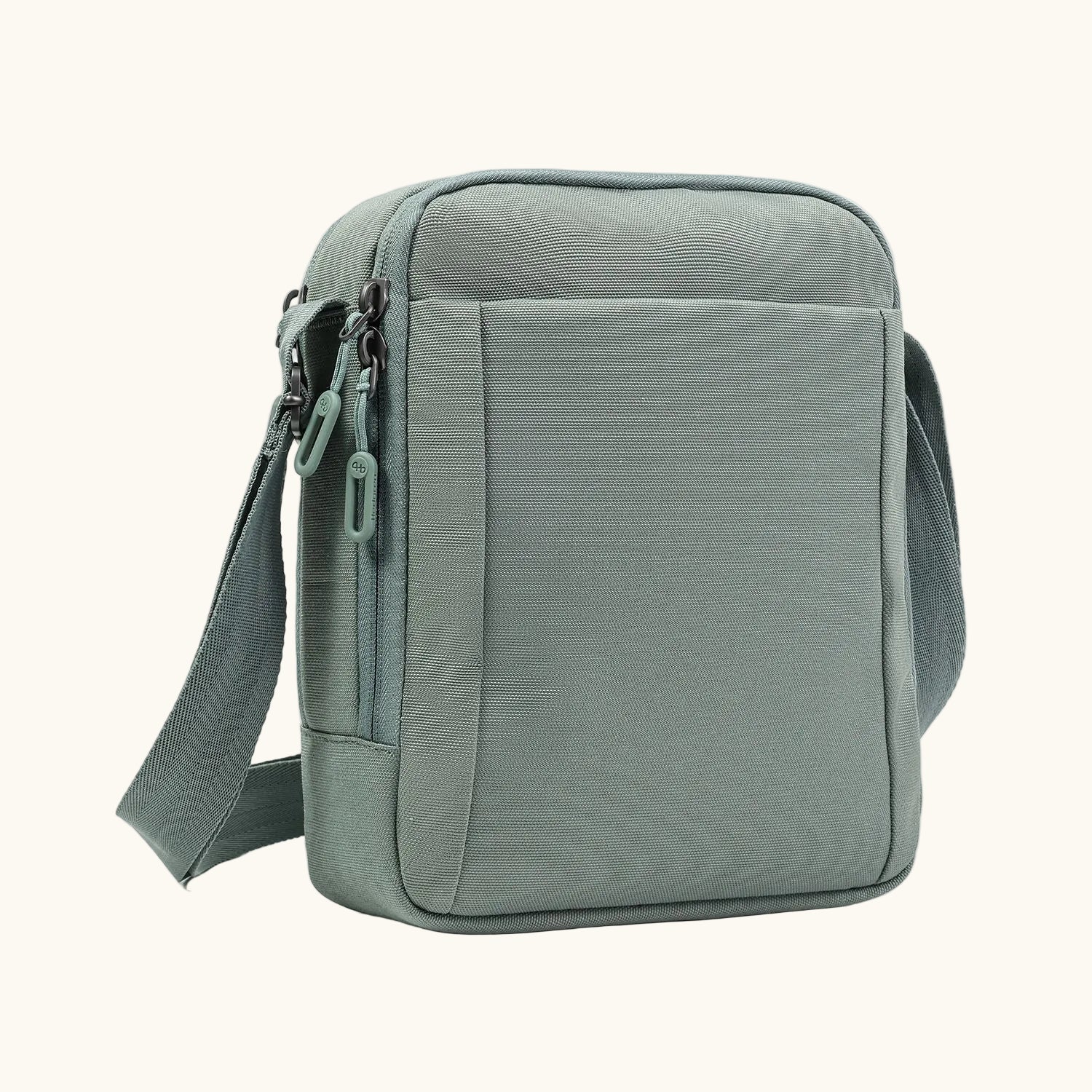 Sage green sling bag by Hedgren with a textured woven fabric, front zipper pocket, and adjustable strap.