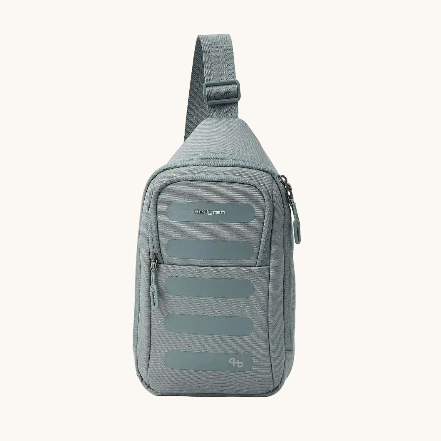 Sage green fabric sling bag by Hedgren with a front zippered pocket, horizontal textured strips, and a small logo.
