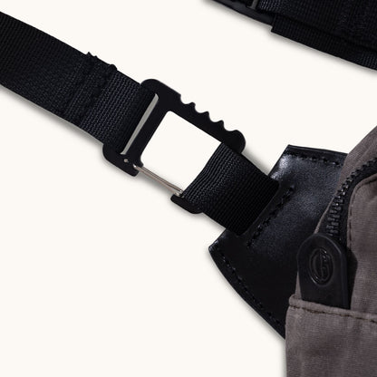 Slate Grey Waxed Canvas Canyon Crossbody Large with a black webbing strap connected by a metal clip to black leather trim and a zippered pocket with a logo pull.