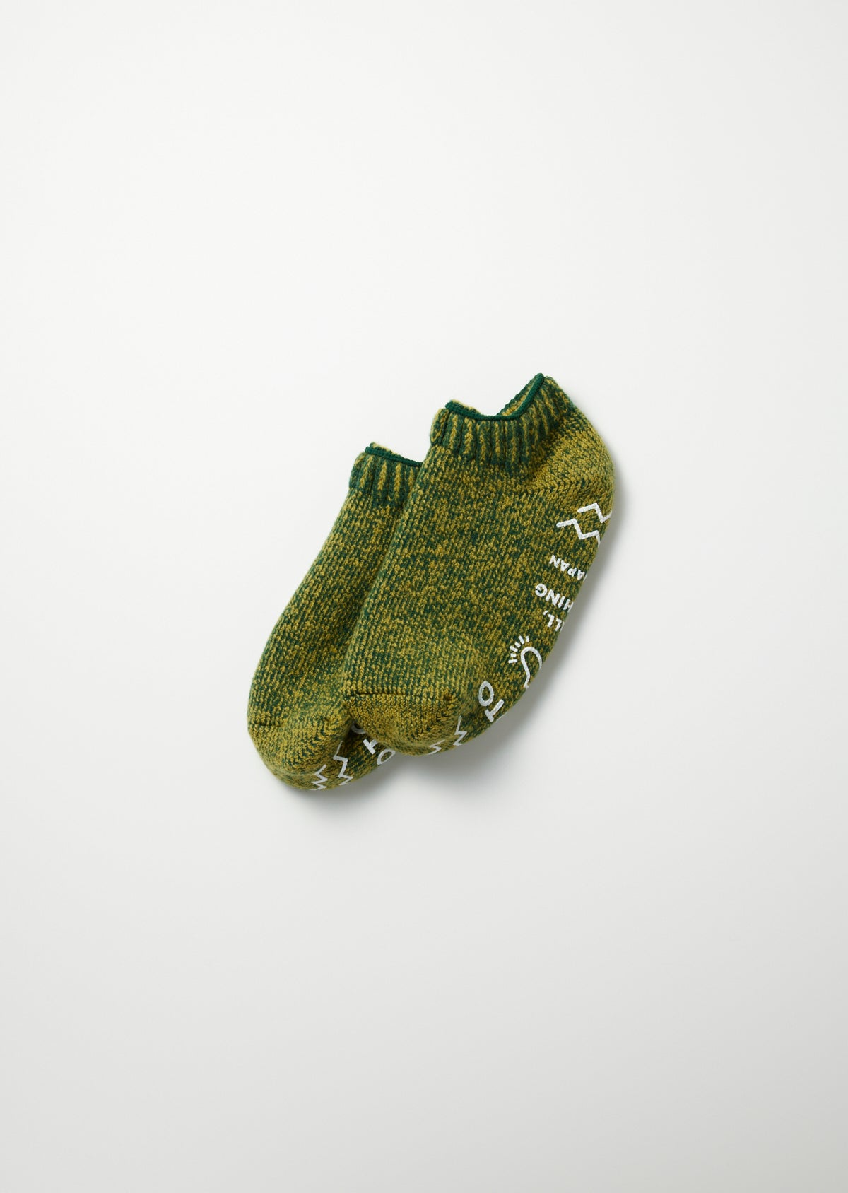 Green marled knit pile sockslippers with white graphics and text, seen from above.