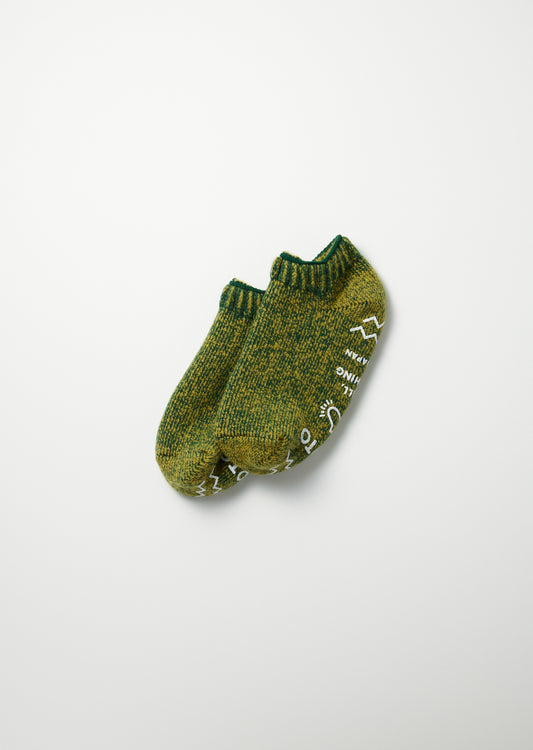 Green marled knit pile sockslippers with white graphics and text, seen from above.