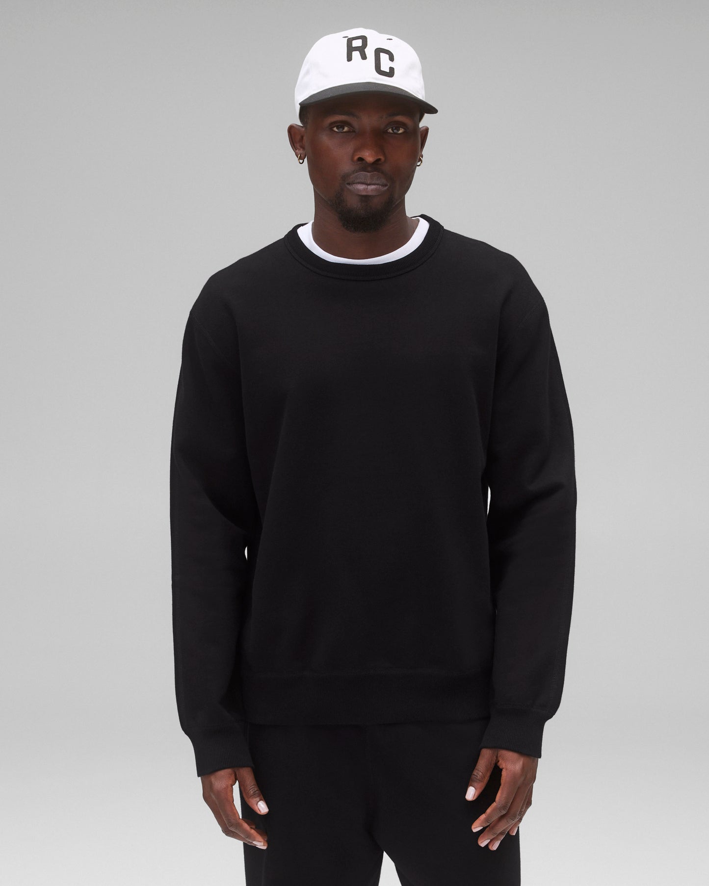 Black Midweight Terry Standard Crewneck worn by a man with a white 'RC' logo cap.