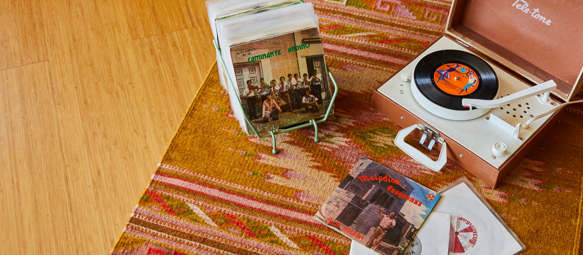 B Grade grab bag item featuring a vintage portable record player, various Latin music records, a patterned rug, and wooden flooring.