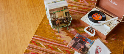 B Grade grab bag item featuring a vintage portable record player, various Latin music records, a patterned rug, and wooden flooring.
