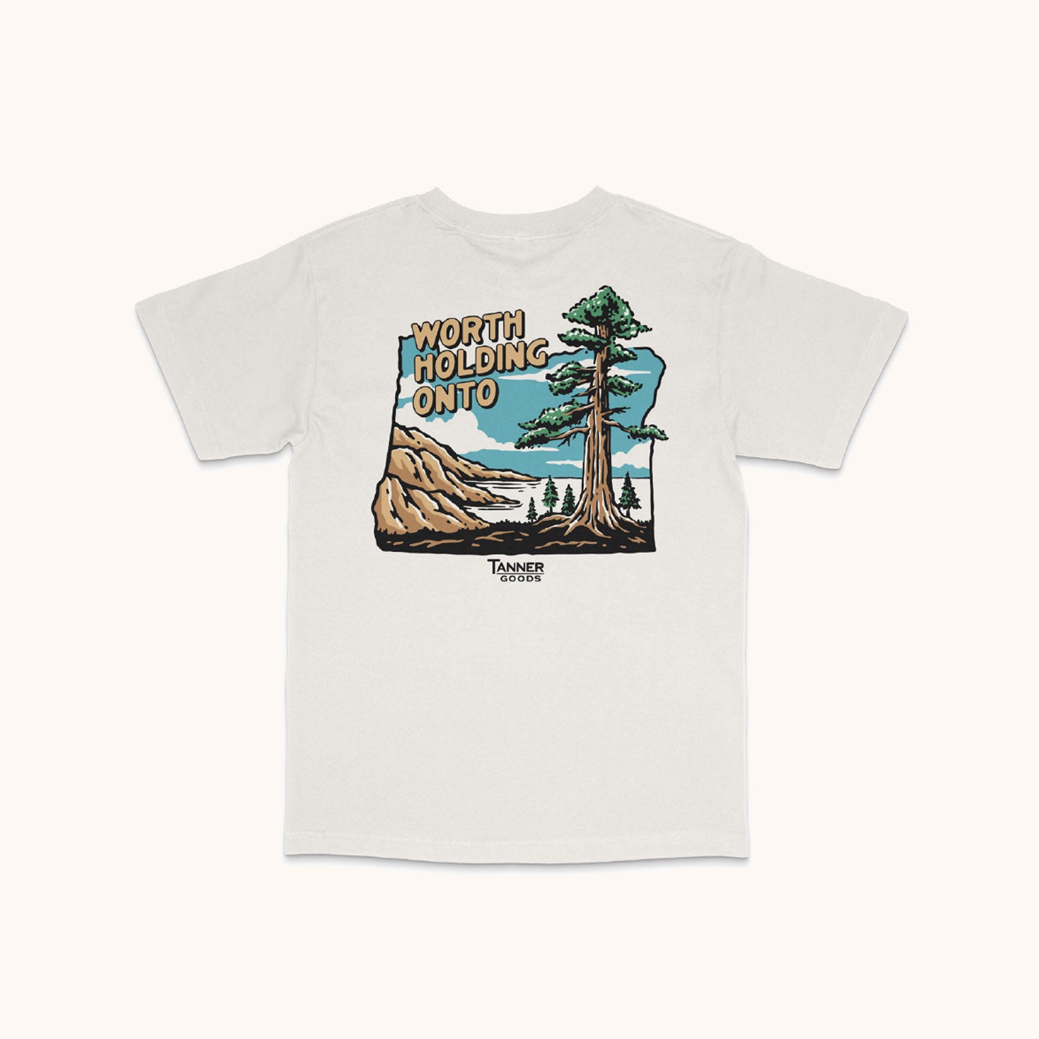 White Adventure T-Shirt by TANNER GOODS with a back graphic of mountains, a lake, a large tree, and "WORTH HOLDING ONTO" text.