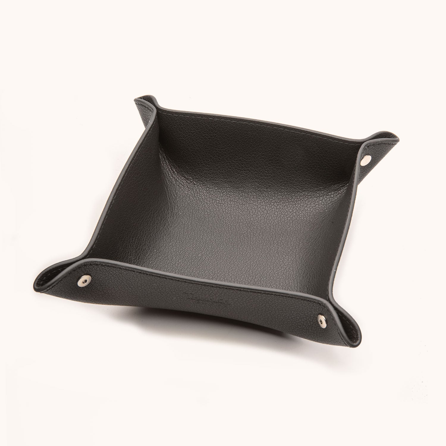 Black recycled leather valet tray with pebbled texture and snapped corners, viewed from an angle.