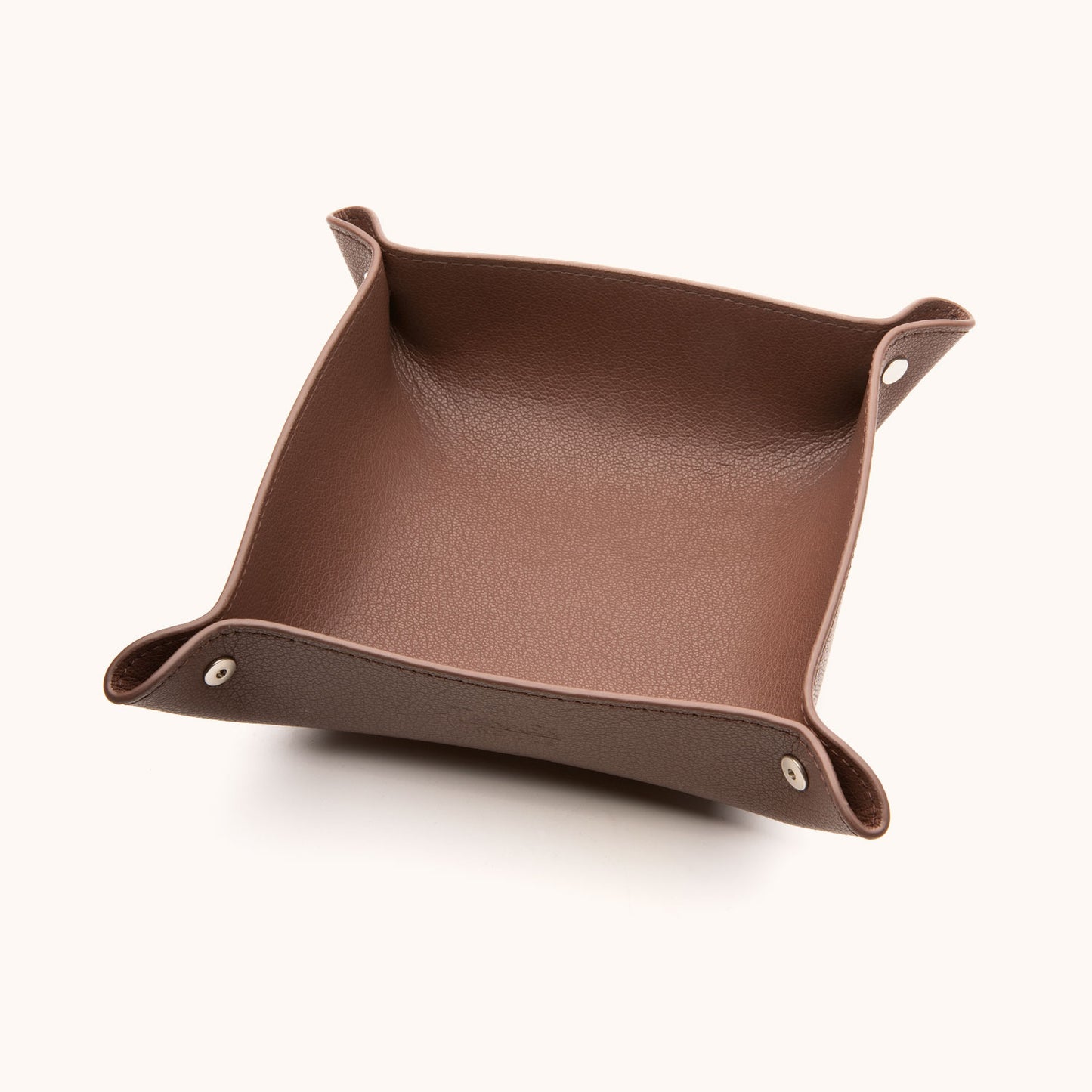 Cognac recycled leather valet tray with folded corners secured by silver snaps, presented at an angle.