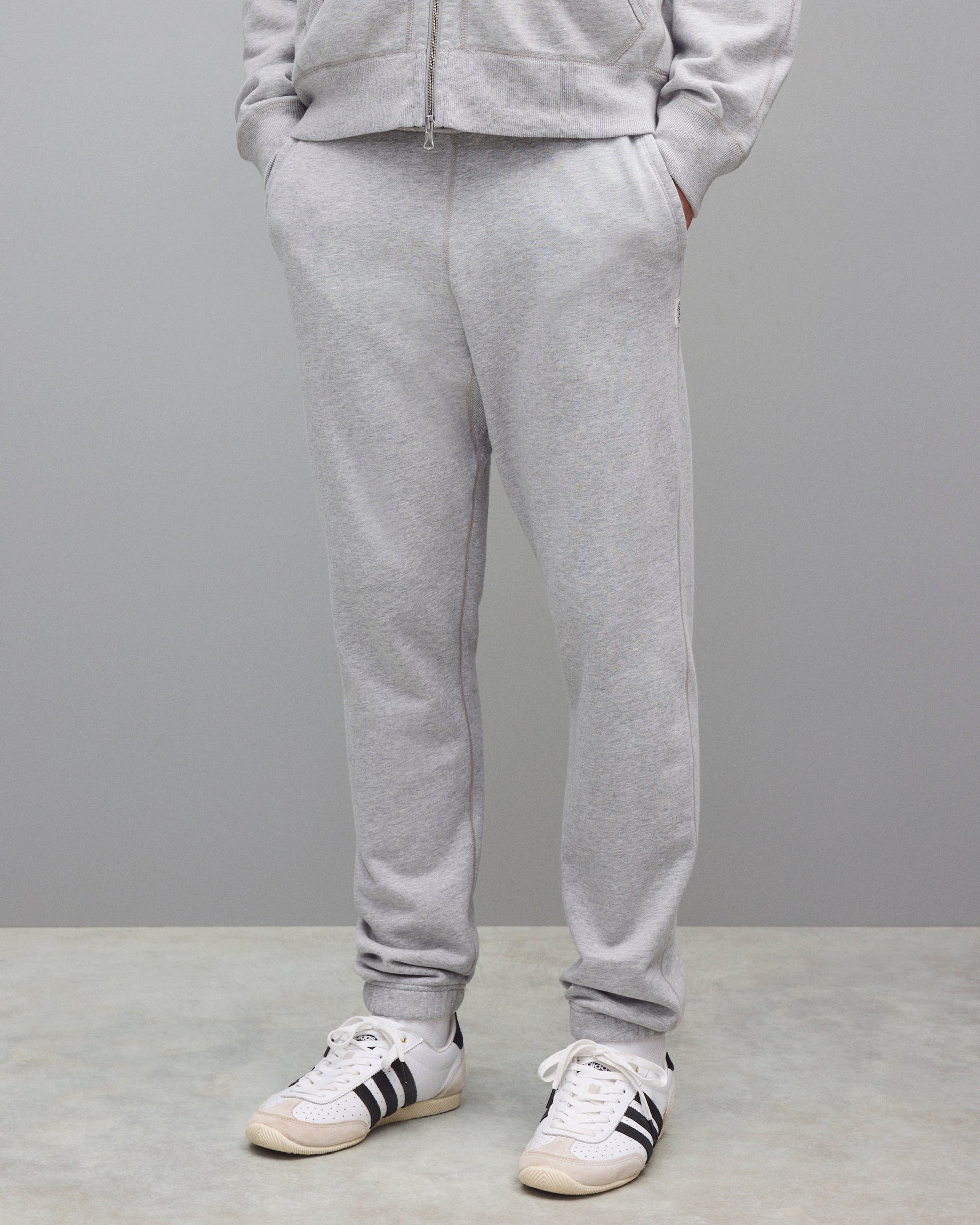 Midweight terry sweatpants in heather grey, styled with a matching zip-up hoodie and white sneakers.