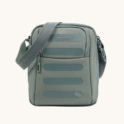 A gray-green sling bag by Hedgren, with a ribbed texture, smooth horizontal accents, and an adjustable strap.