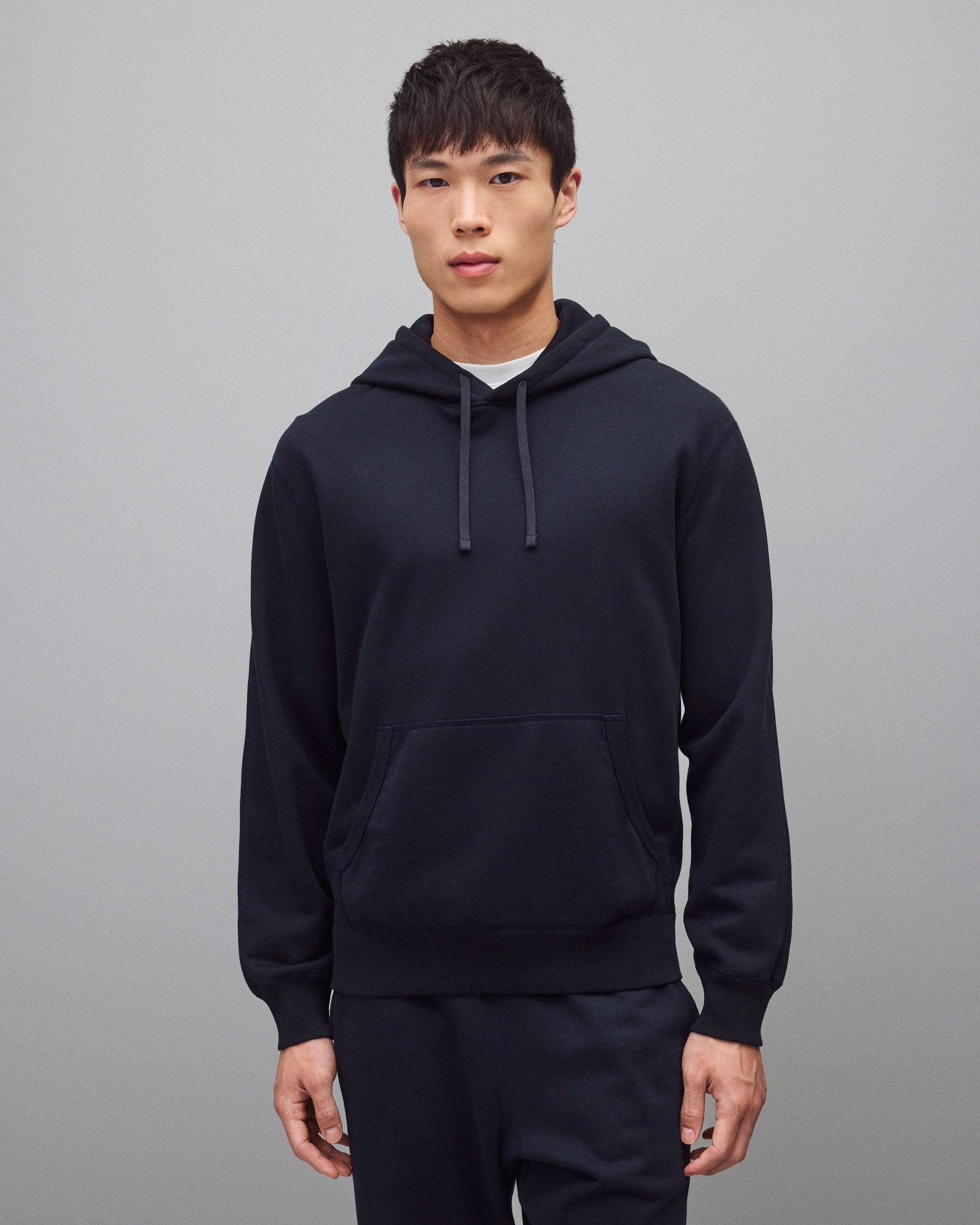 Navy blue Midweight Terry Standard Hoodie with drawstrings and a front pouch pocket, worn by a male model.