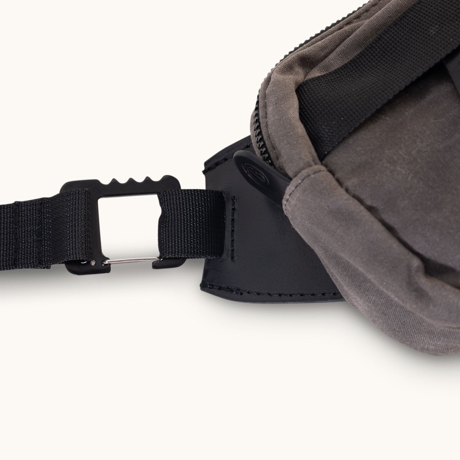 Slate grey waxed canvas Canyon Crossbody Mini bag, showing a black strap connecting to a silver metal hook-and-pin buckle, cropped.