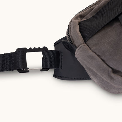 Slate grey waxed canvas Canyon Crossbody Mini bag, showing a black strap connecting to a silver metal hook-and-pin buckle, cropped.