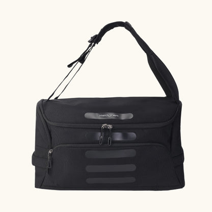 A green Hedgren Sojourn duffle bag with multiple compartments and a rolled-up design, featuring a shoulder strap and a top handle.