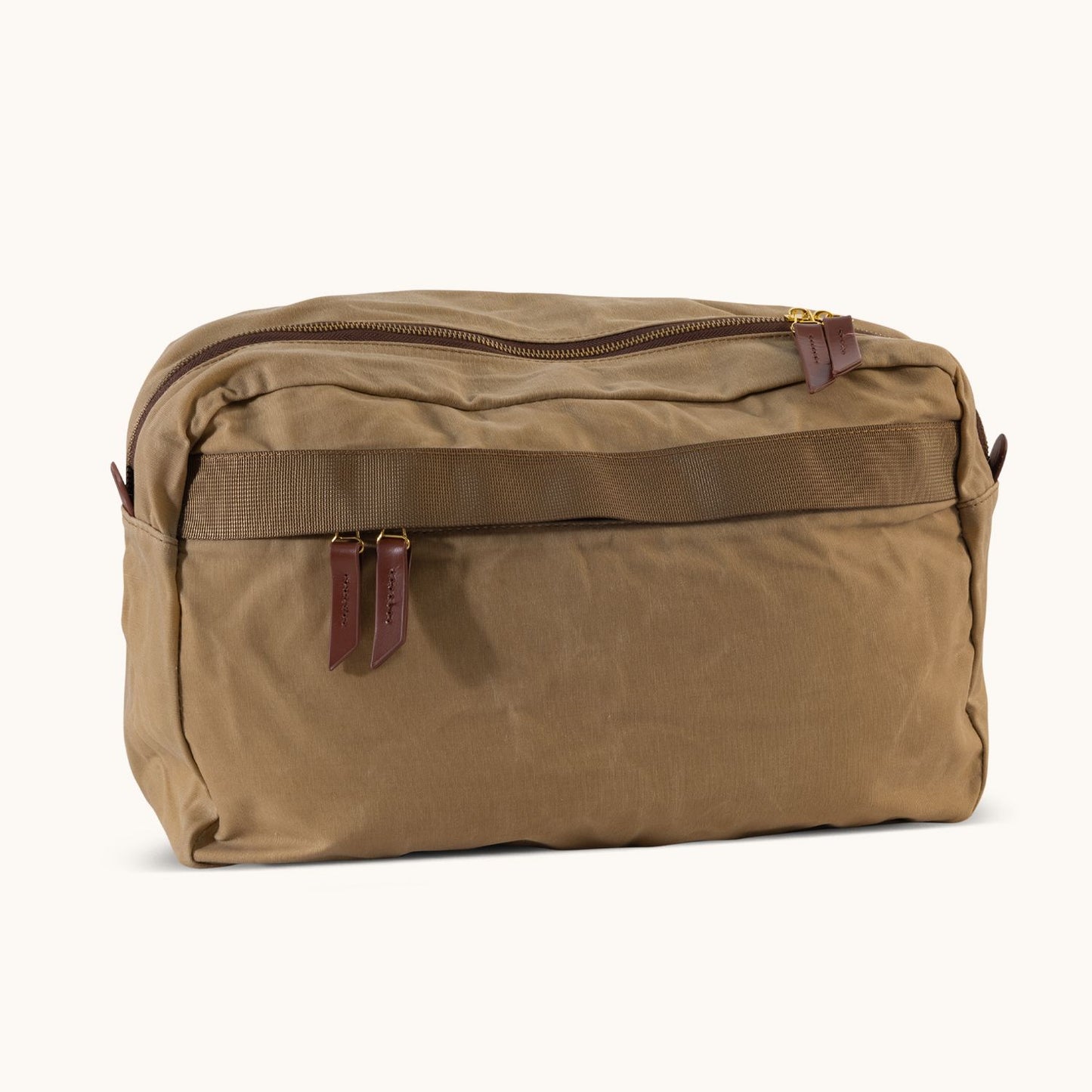 A large utility tan waxed canvas crossbody bag with a zippered top, two brown leather pulls, and a front horizontal strap.