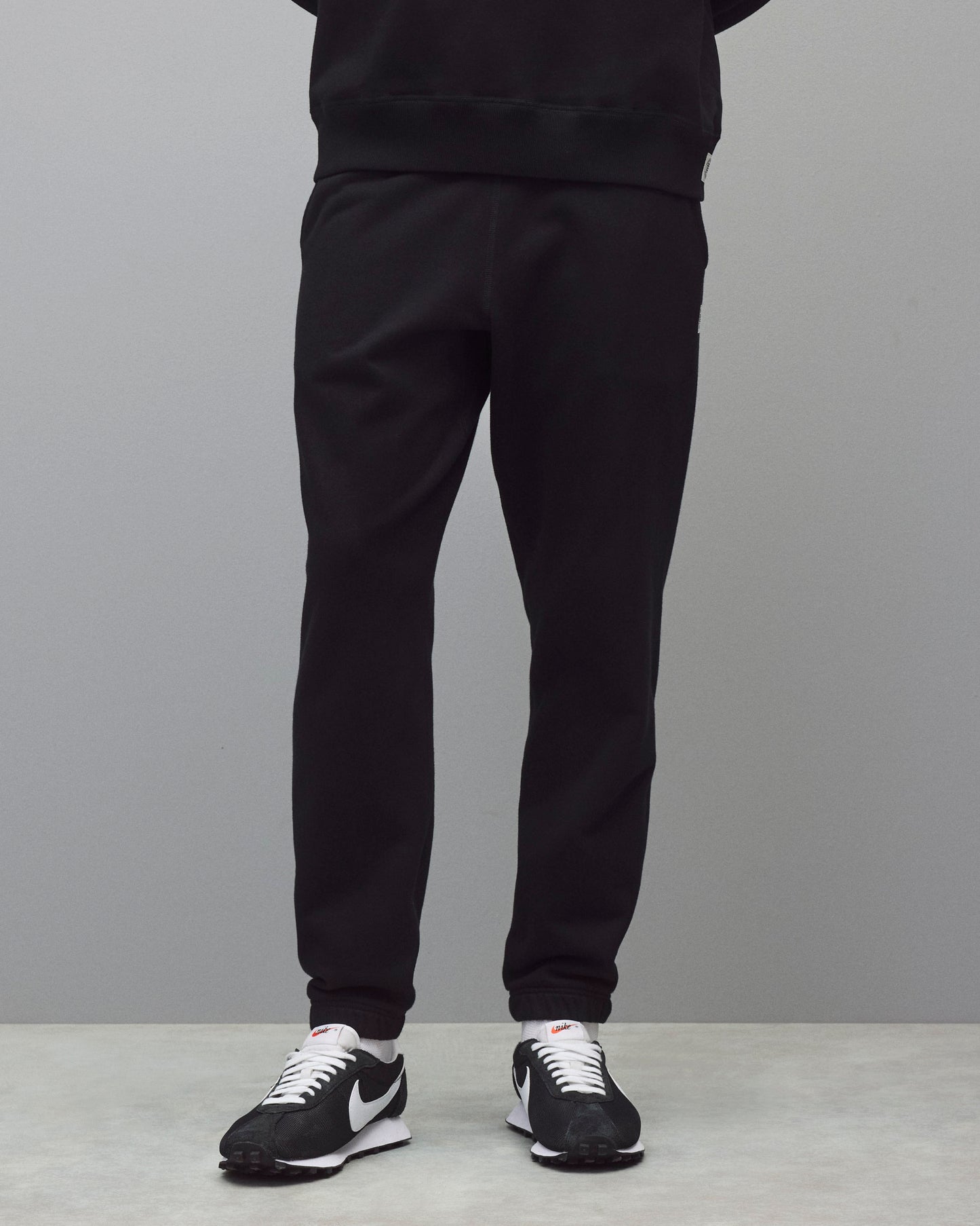 Black midweight terry standard sweatpants featuring a ribbed waistband and cuffs, worn with white socks and black sneakers.