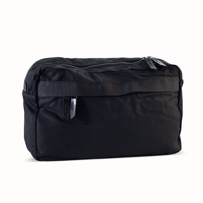 Large black waxed canvas crossbody bag featuring a main zipper and a horizontal front webbing strap.