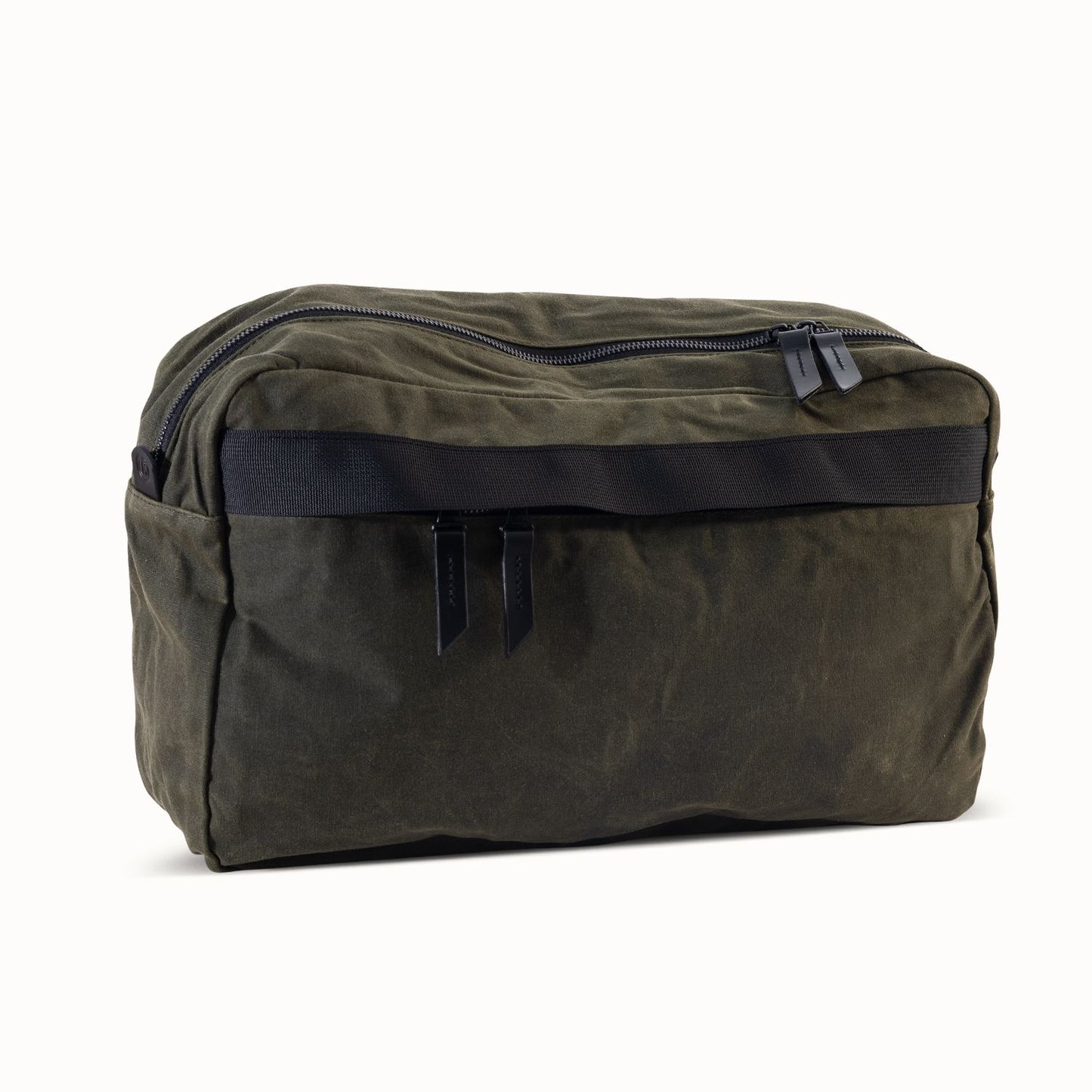 Juniper green waxed canvas crossbody bag with a black front strap and dual zipper pulls.