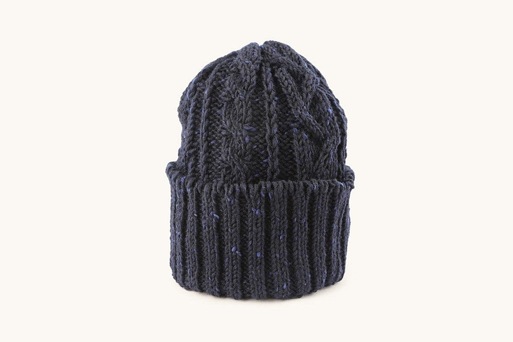 Dark blue cable knit cap with a ribbed cuff, speckled with lighter blue flecks.