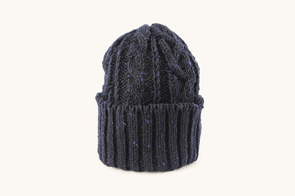 Dark blue cable knit cap with a ribbed cuff, speckled with lighter blue flecks.